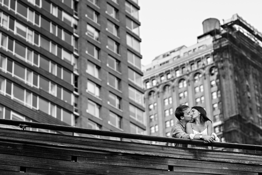A couple kiss on the bridge in front of their apartment building in manhattan for their engagement session.